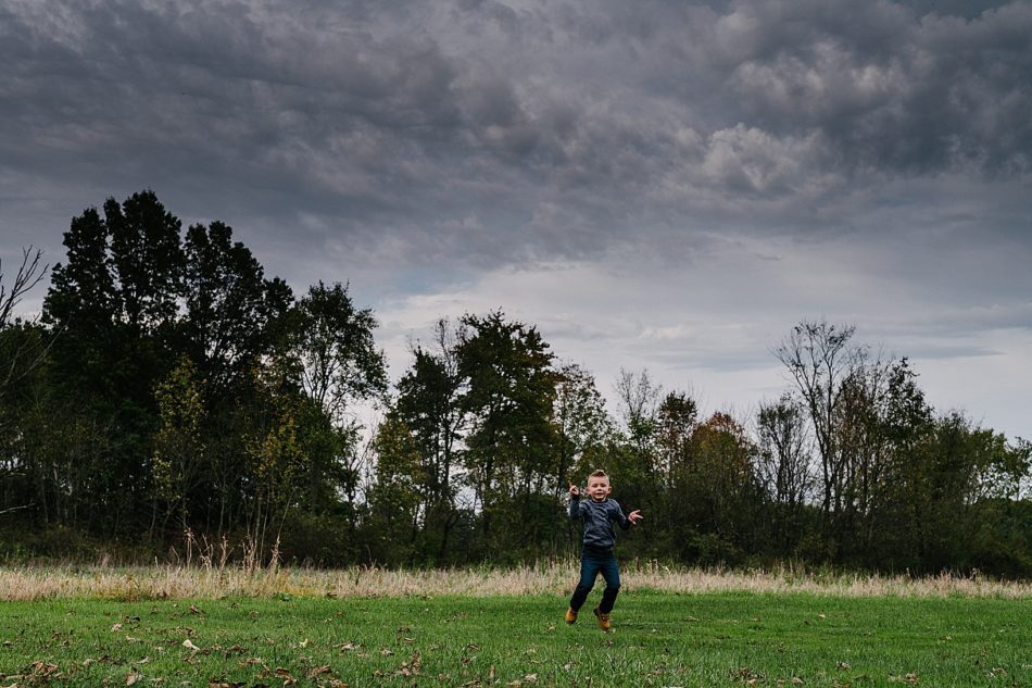 Young boy jumps and gives the "rock on" hand sign in the middle of a grass field in North Jackson Ohio.
