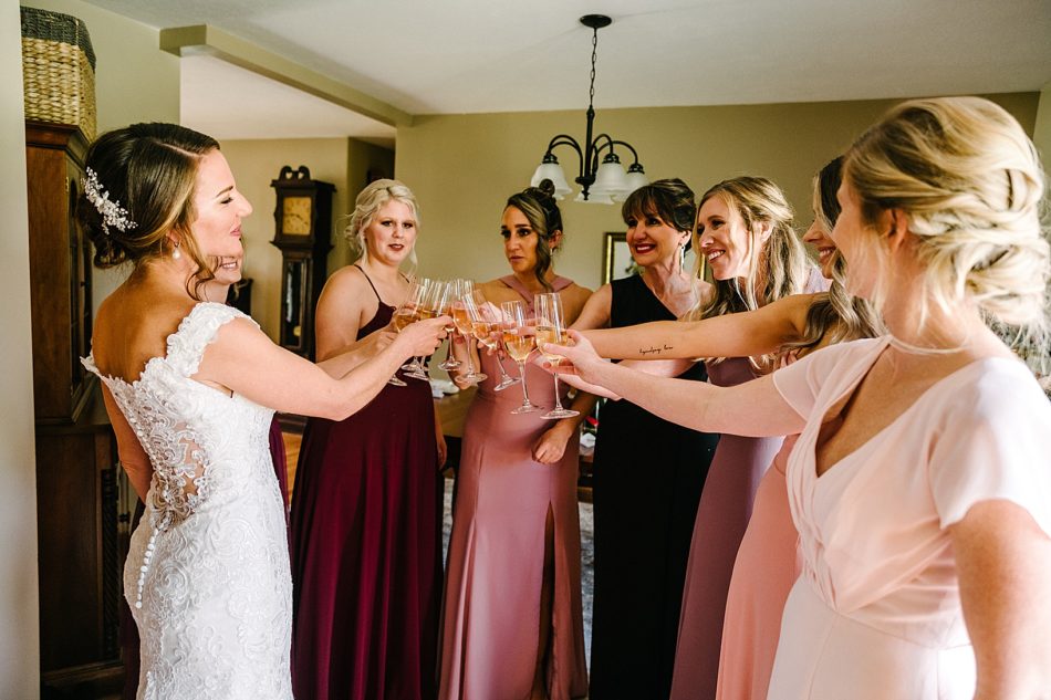 Bride and bridal party all cheers with champagne glasses