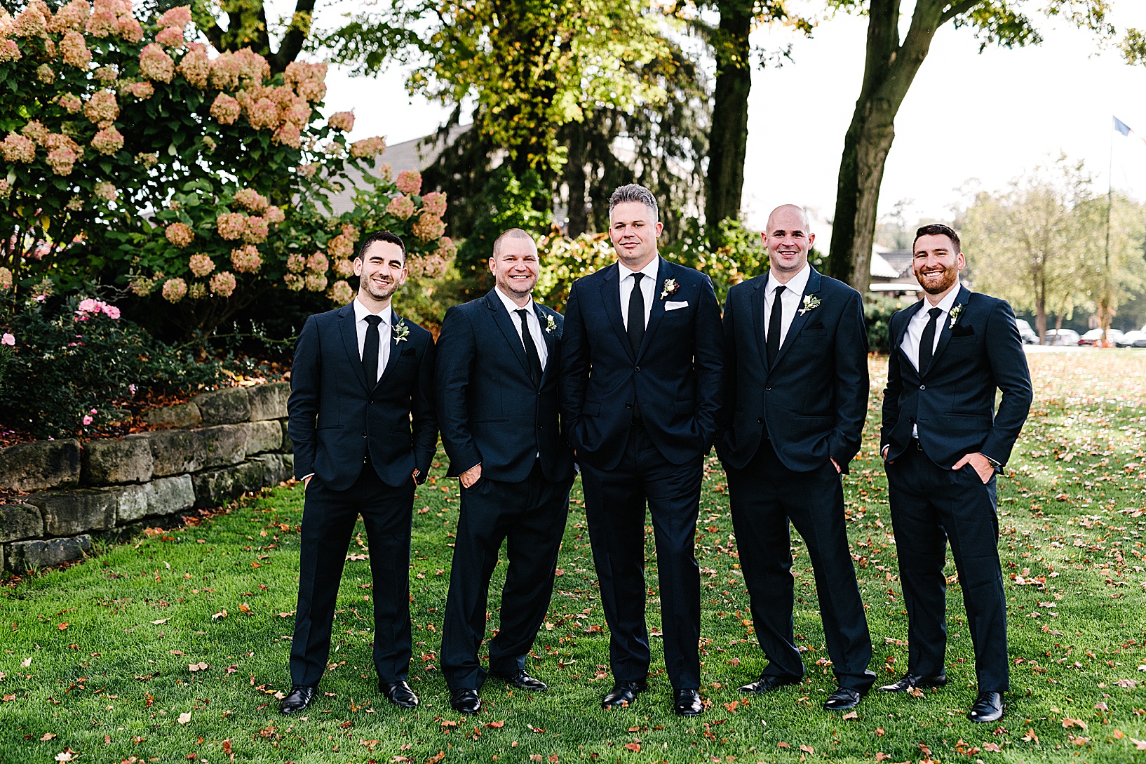 Groom and groomsmen hand and smiles on the lawn of the Lake Club