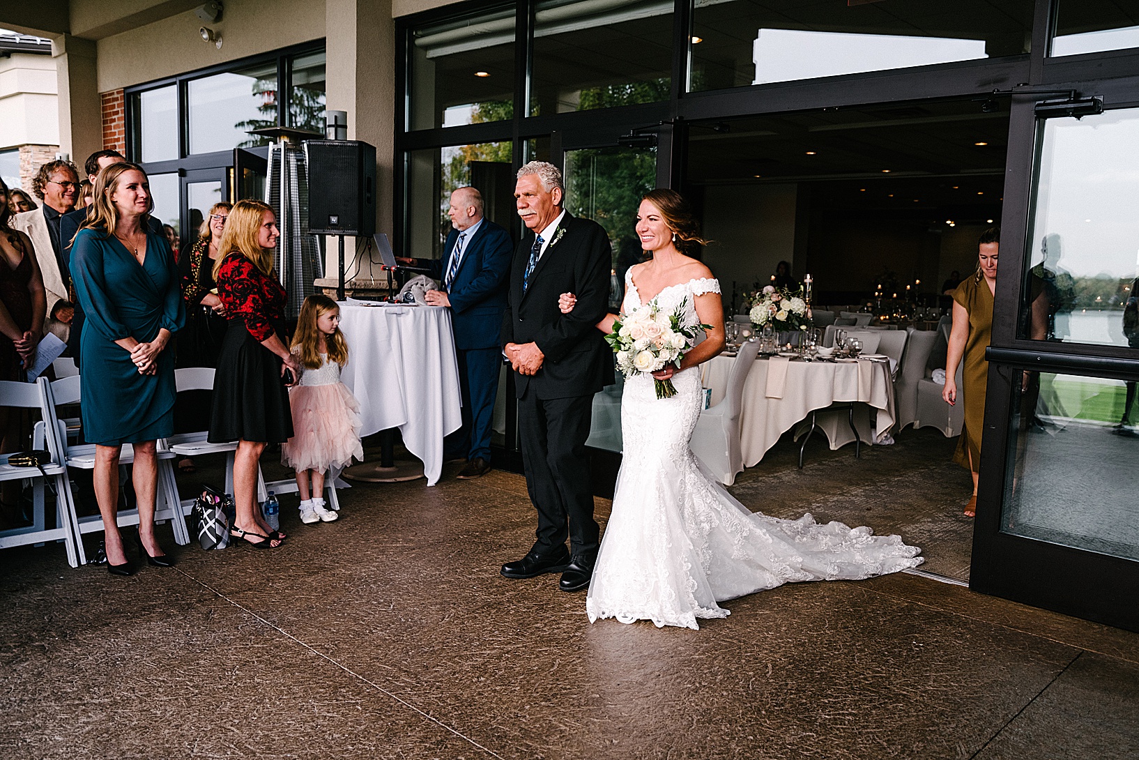 Bride walking down the aisle with her father, exiting the sliding doors of the Lake Club.