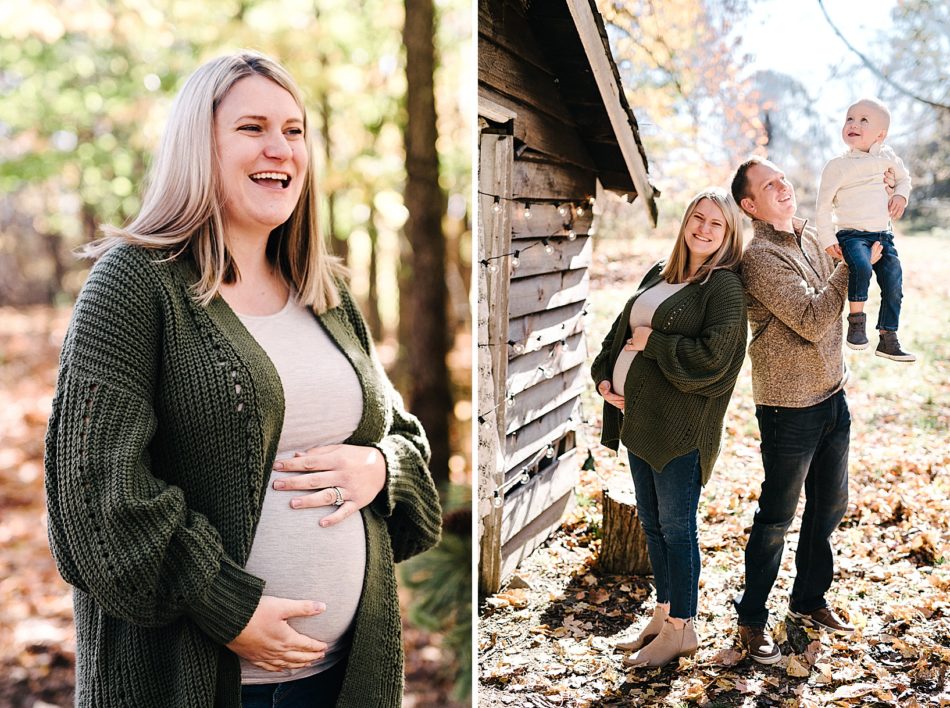 Pregnant blond woman in dark green, chunky knit cardigan holds her belly and smiles.