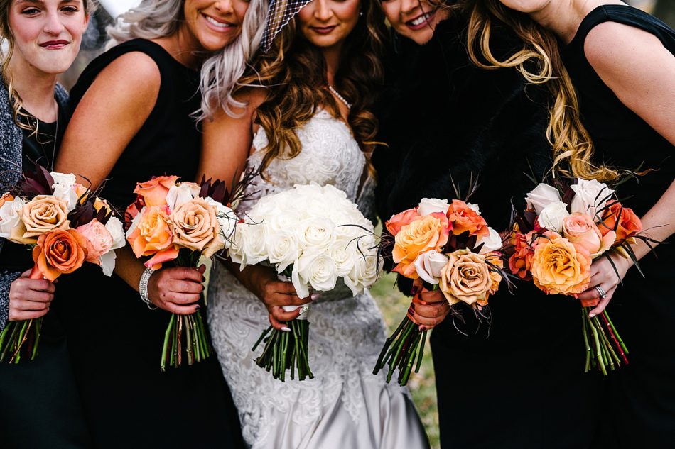 The brides white rose bouquet and the bridal parties orange, white, yellow, and burgundy bouquets.