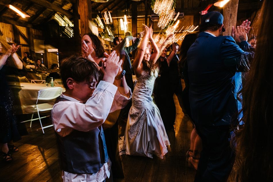Wedding guests and the bride clapping their hands above their heads on the dance floor at Peacock Ridge