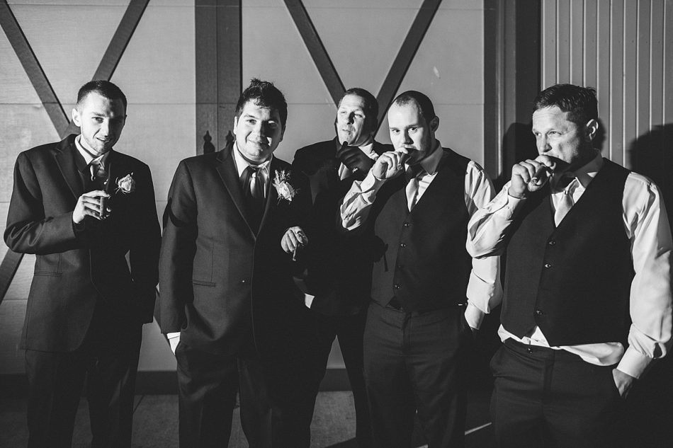 Grooms party dressed in their suits smoking cigars