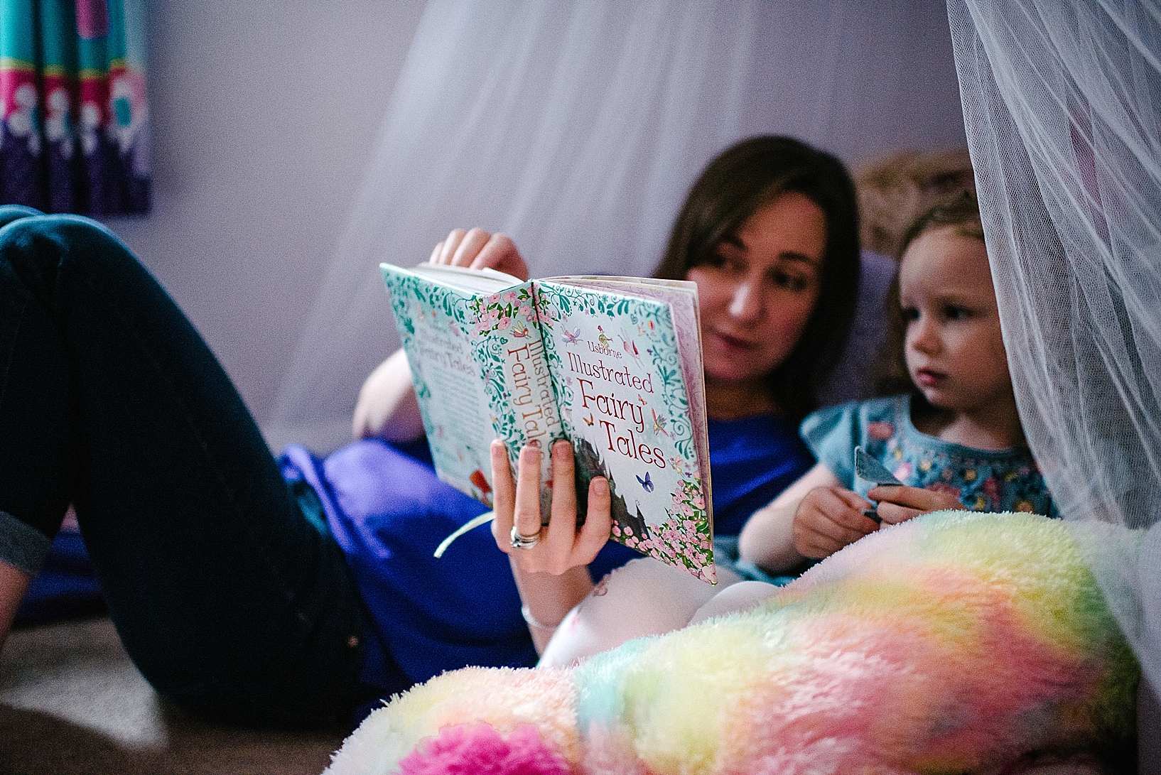 mother reading book of fairy tales to daughter