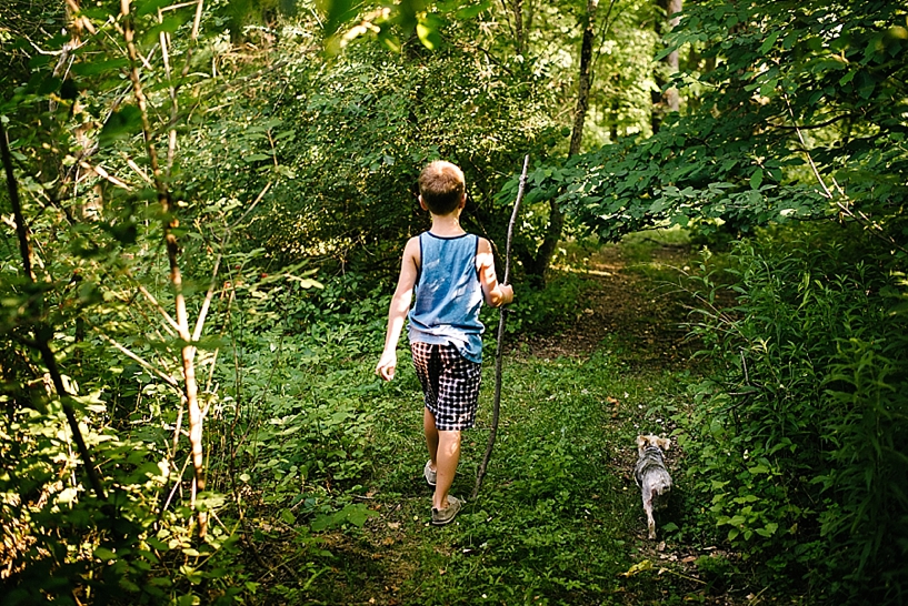 little boy and dog walking through the woods