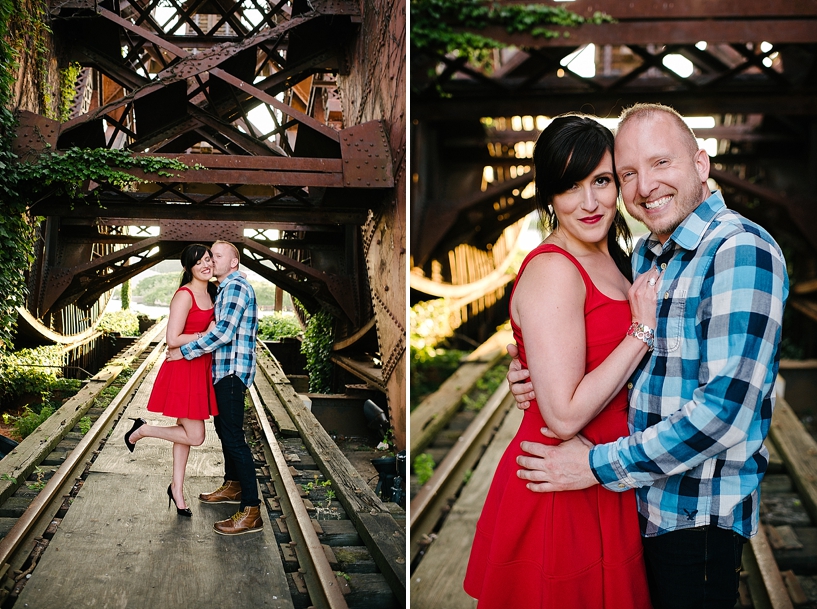girl wearing red dress and heels with fiance in blue plaid by ivy covered bridge