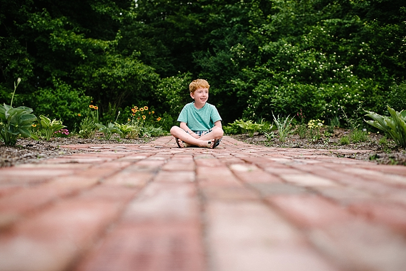 redhead boy sitting on brick path