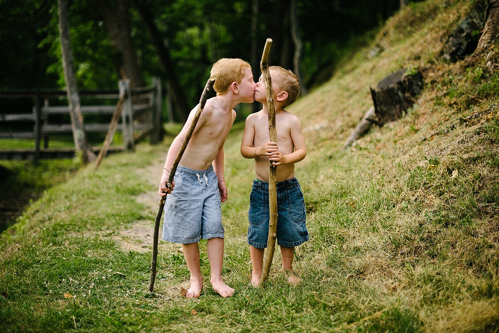 brothers with walking sticks and no shirts kissing