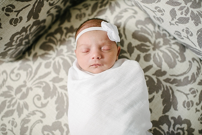 newborn wrapped in white blanket on chair
