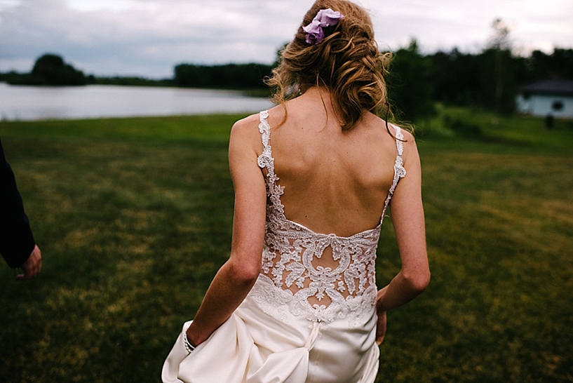 bride in lace gown walking towards lake