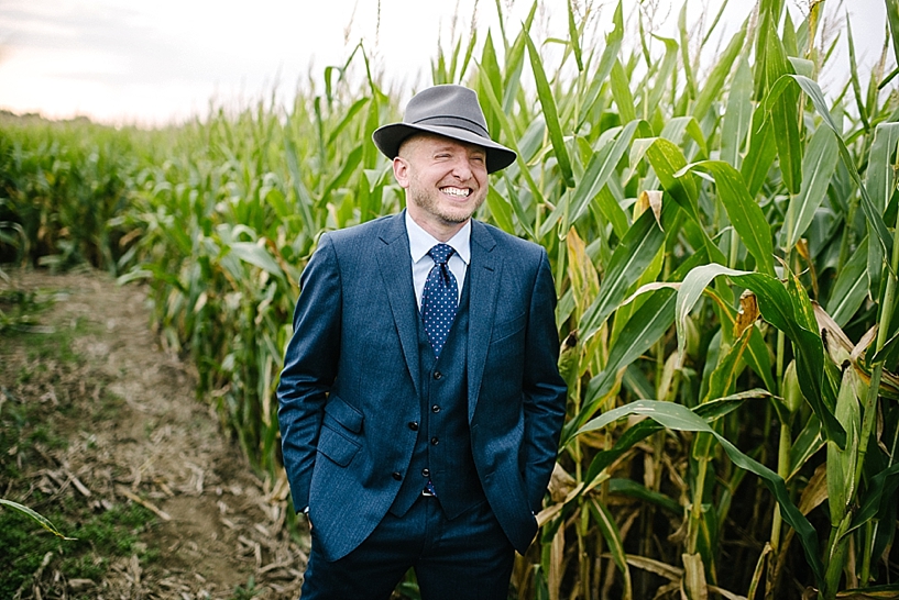 groom in navy suit and fedora laughing
