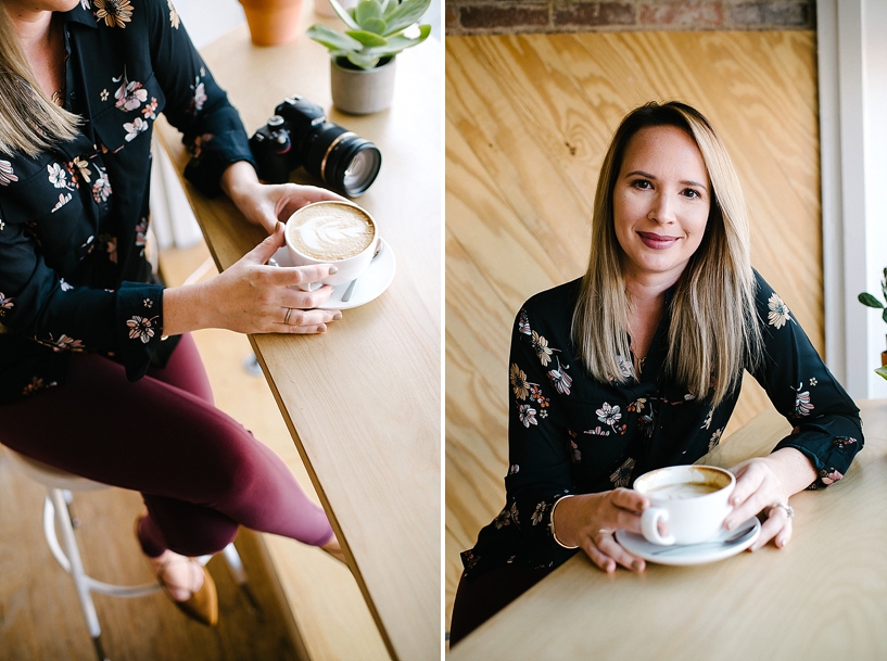 Woman in coffee shop holding latte with camera nearby
