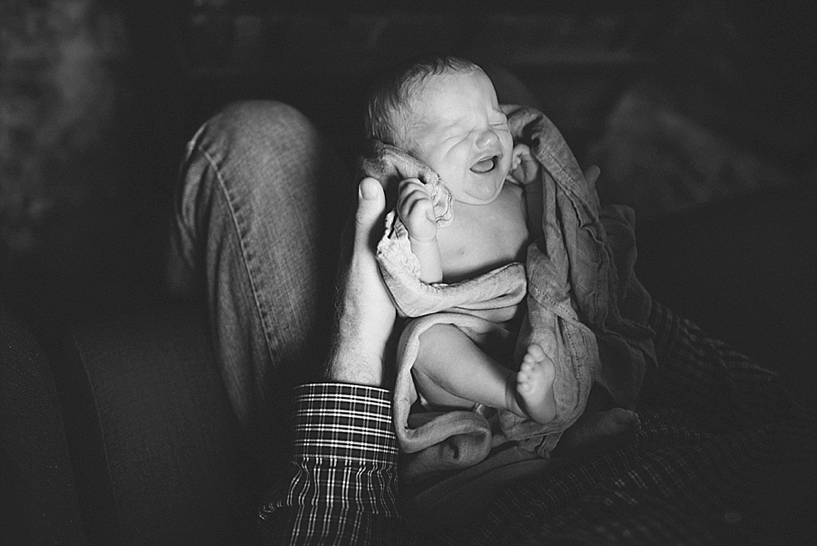 newborn baby crying in father's lap