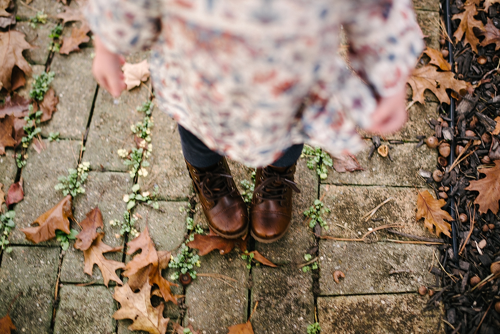 toddler girl wearing brown boots standing on brick path
