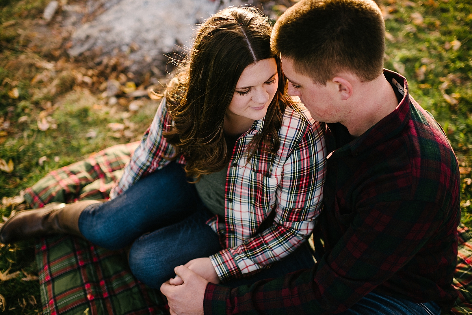 couple wearing flannel sitting by campfire