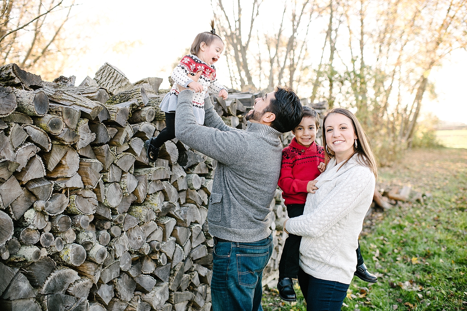 family standing in front of log pile laughing and smiling