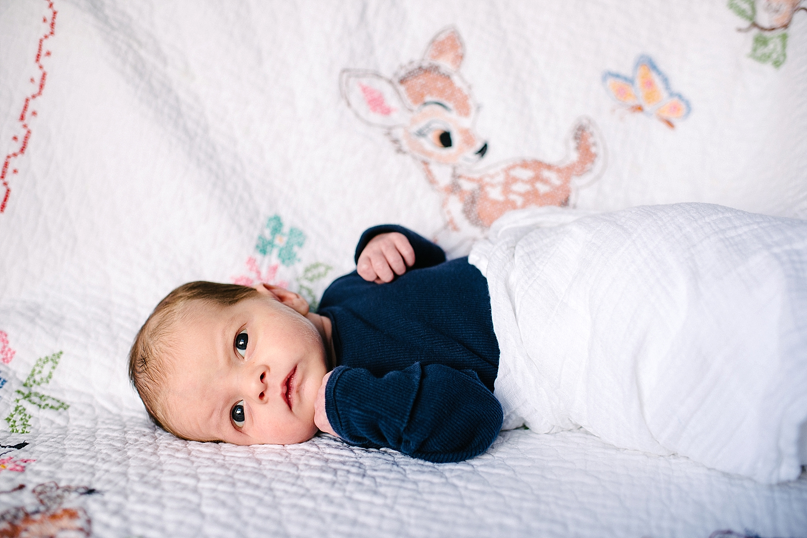 newborn baby boy laying on Bambi blanket embroidered by great grandmother