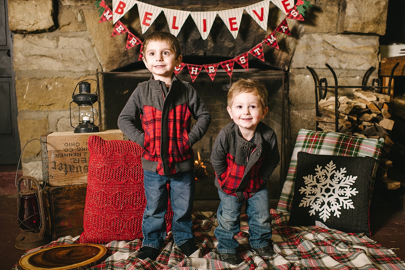 toddler brothers wearing matching vests standing in front of fireplace with Christmas decorations