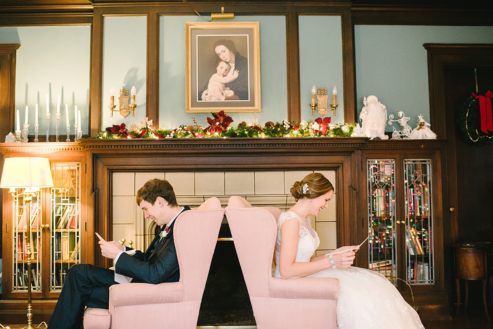 bride and groom sitting in front of fireplace reading letters
