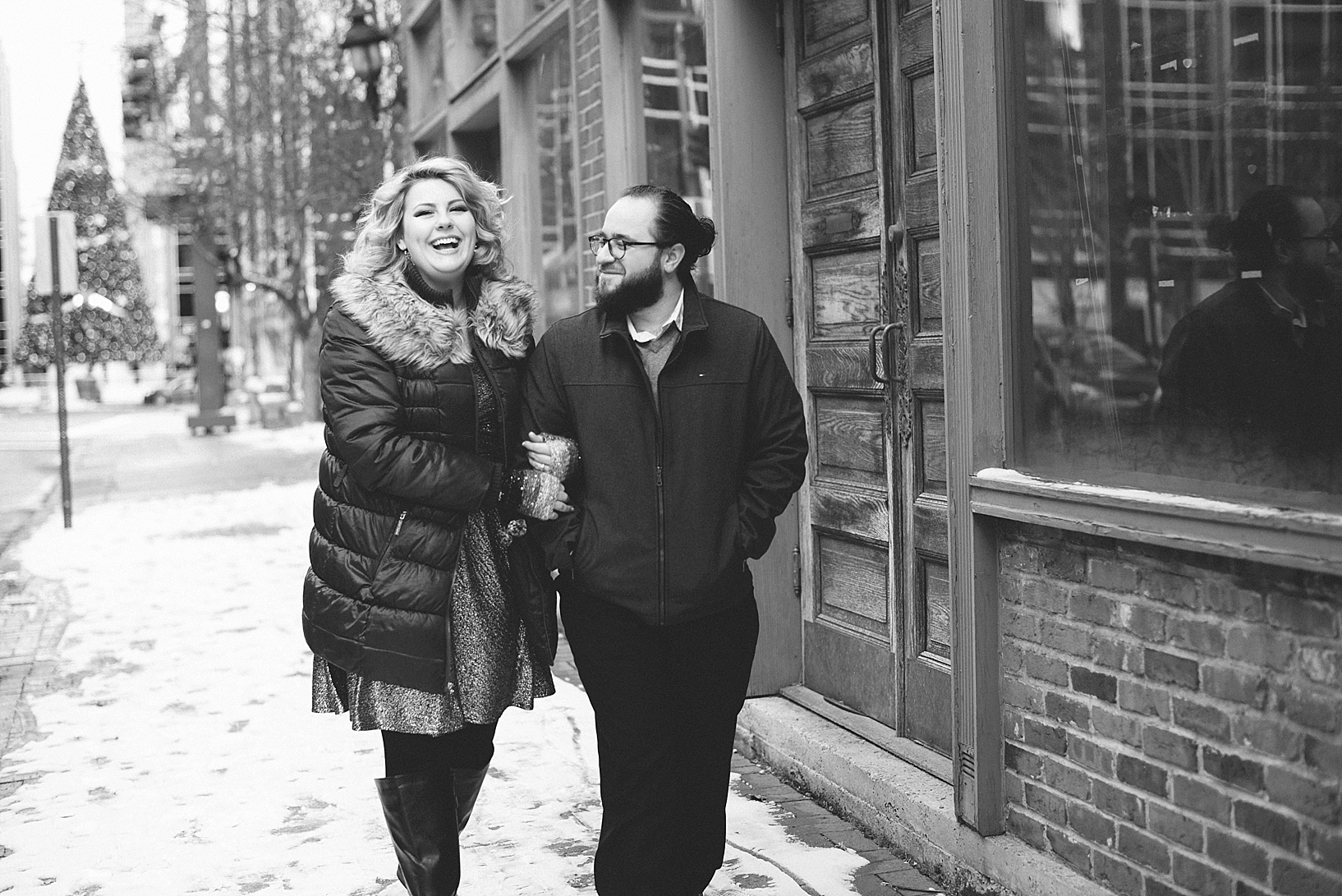 couple linking arms walking down city sidewalk in winter
