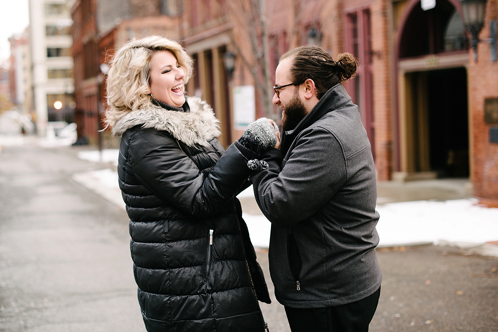 man with man bun and glasses kissing fiance's hand