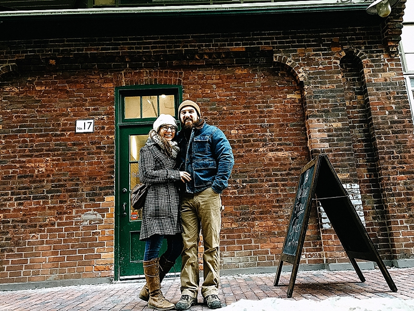 couple standing in front of brick building in the Distillery District of Toronto