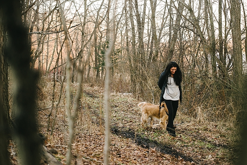 woman in grey hoodie walking golden retriever through woods
