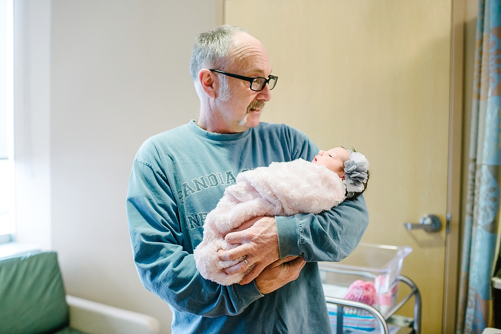Grandpa holding new granddaughter in hospital room