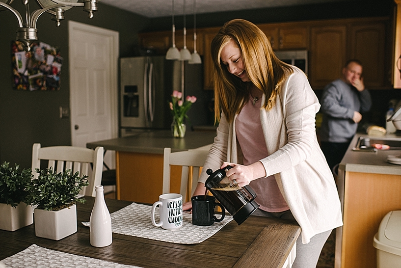 woman pouring french press coffee into mugs at kitchen table