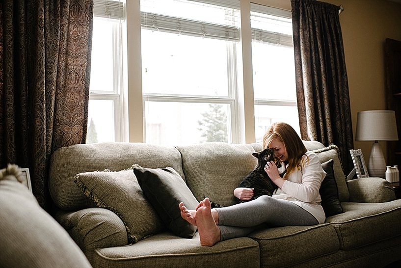 woman in grey leggings sitting on couch with cat in her lap