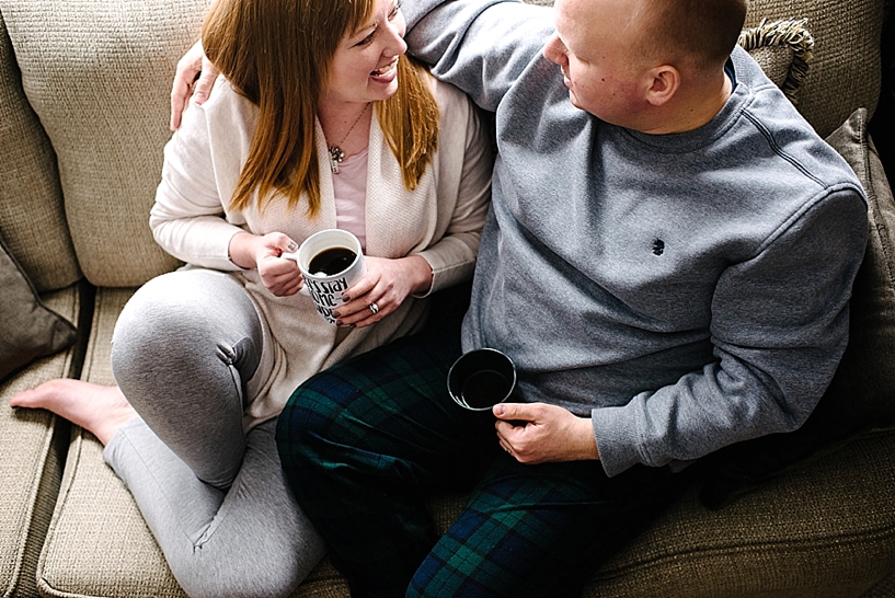 couple sitting on couch drinking coffee in pajamas