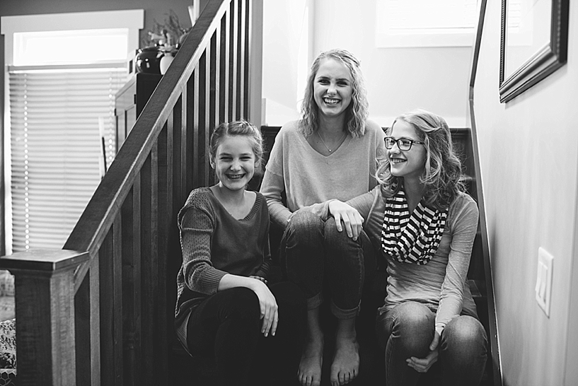 three teenage sisters sitting on stairs of their home smiling