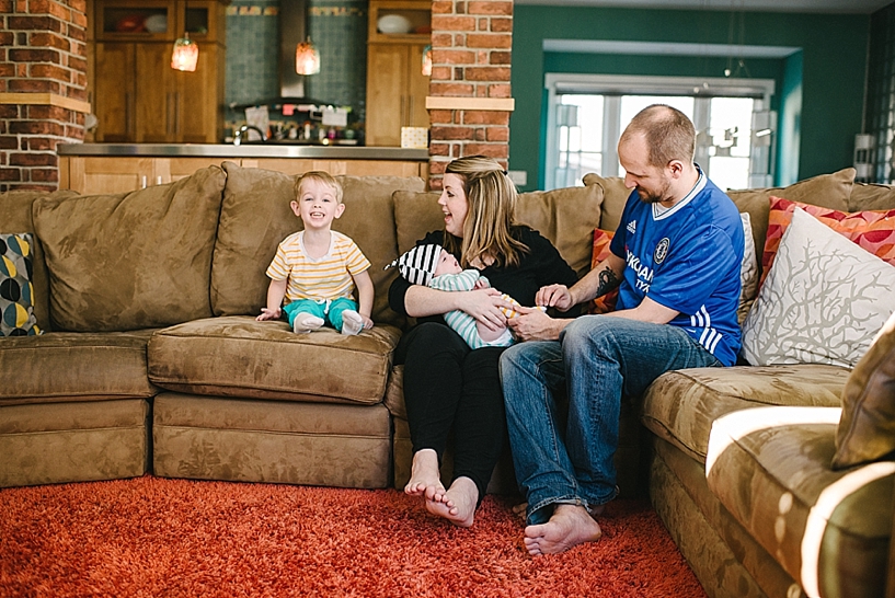 parents sitting on couch holding baby with toddler boy