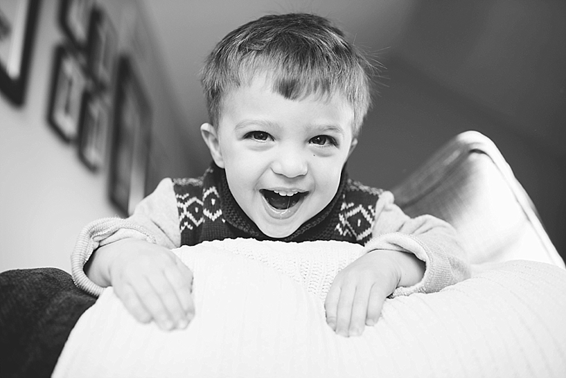 toddler boy looking over side of couch laughing