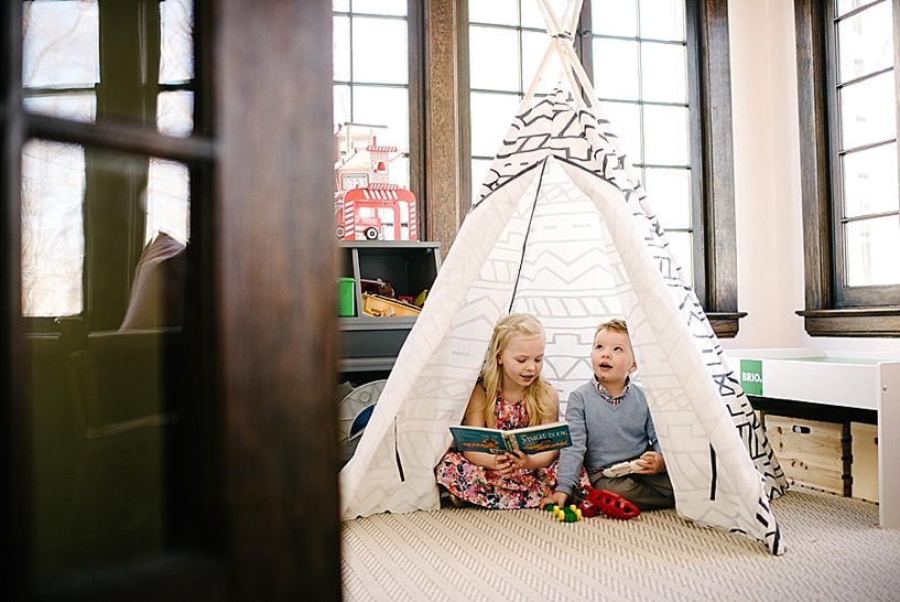 boy and girl sitting in teepee reading books