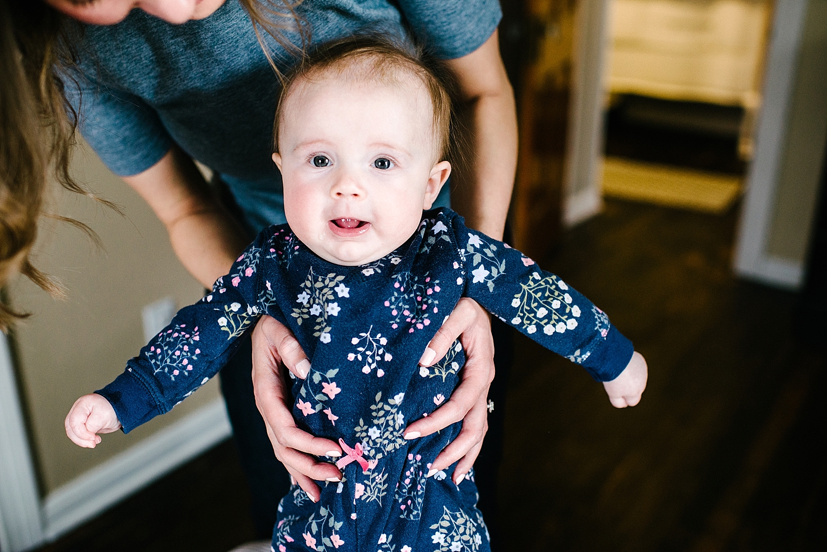 mother holding baby girl wearing floral romper