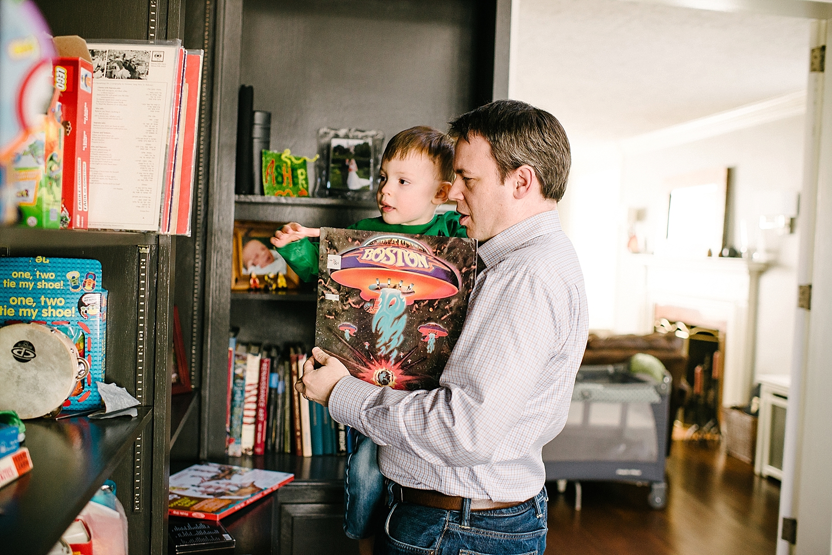 father and son picking out record from bookshelf