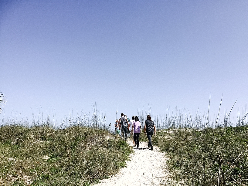group walking up sand dunes to beach