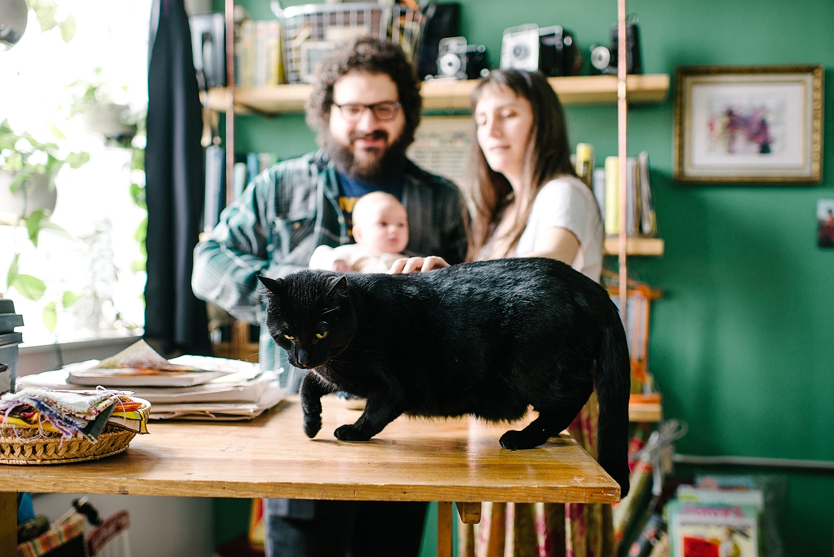black cat jumped up on home art studio desk in front of family