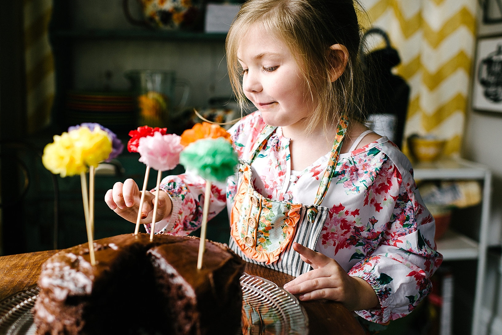 young girl sticking finger in icing on chocolate cake