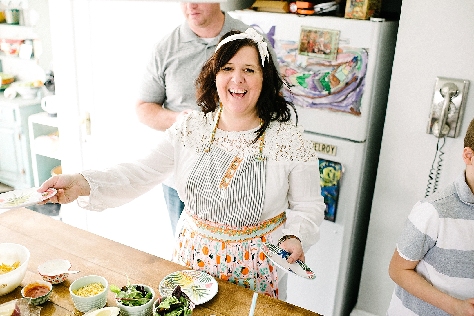 woman wearing patterned apron handing out plates to and laughing
