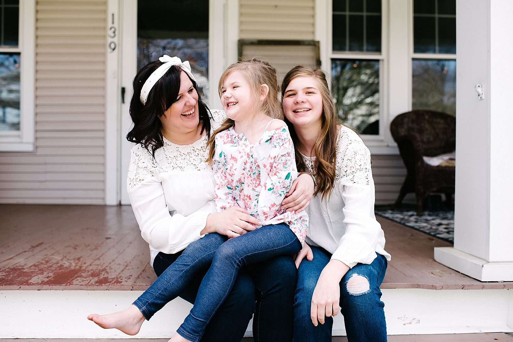 mother sitting on front porch with two daughters laughing