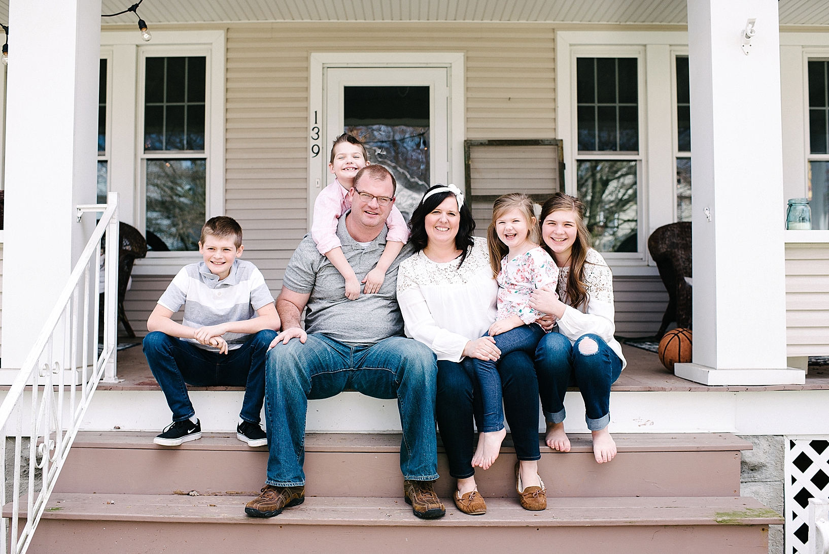 family sitting on porch steps of their home