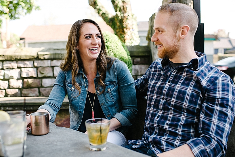 couple sitting at outdoor patio drinking cocktails and laughing