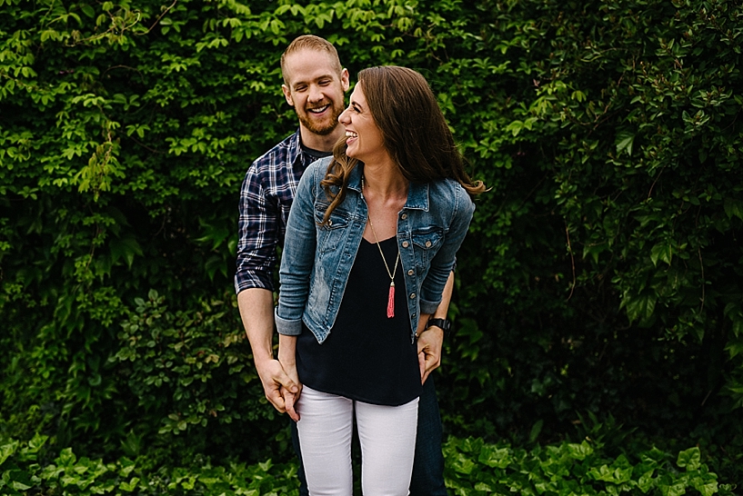 man and woman standing in front of ivy wall laughing