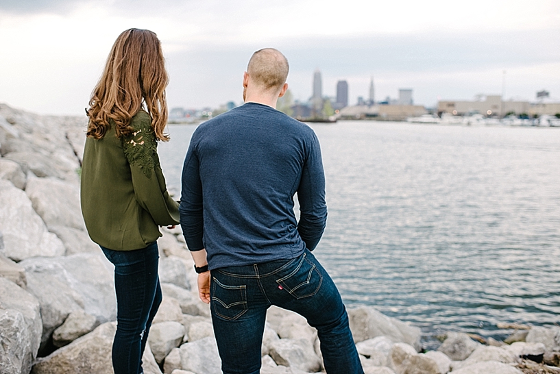 woman wearing olive shirt and jeans and man wearing navy shirt and jeans climbing on rocks at Edgewater State Park in front of skyline