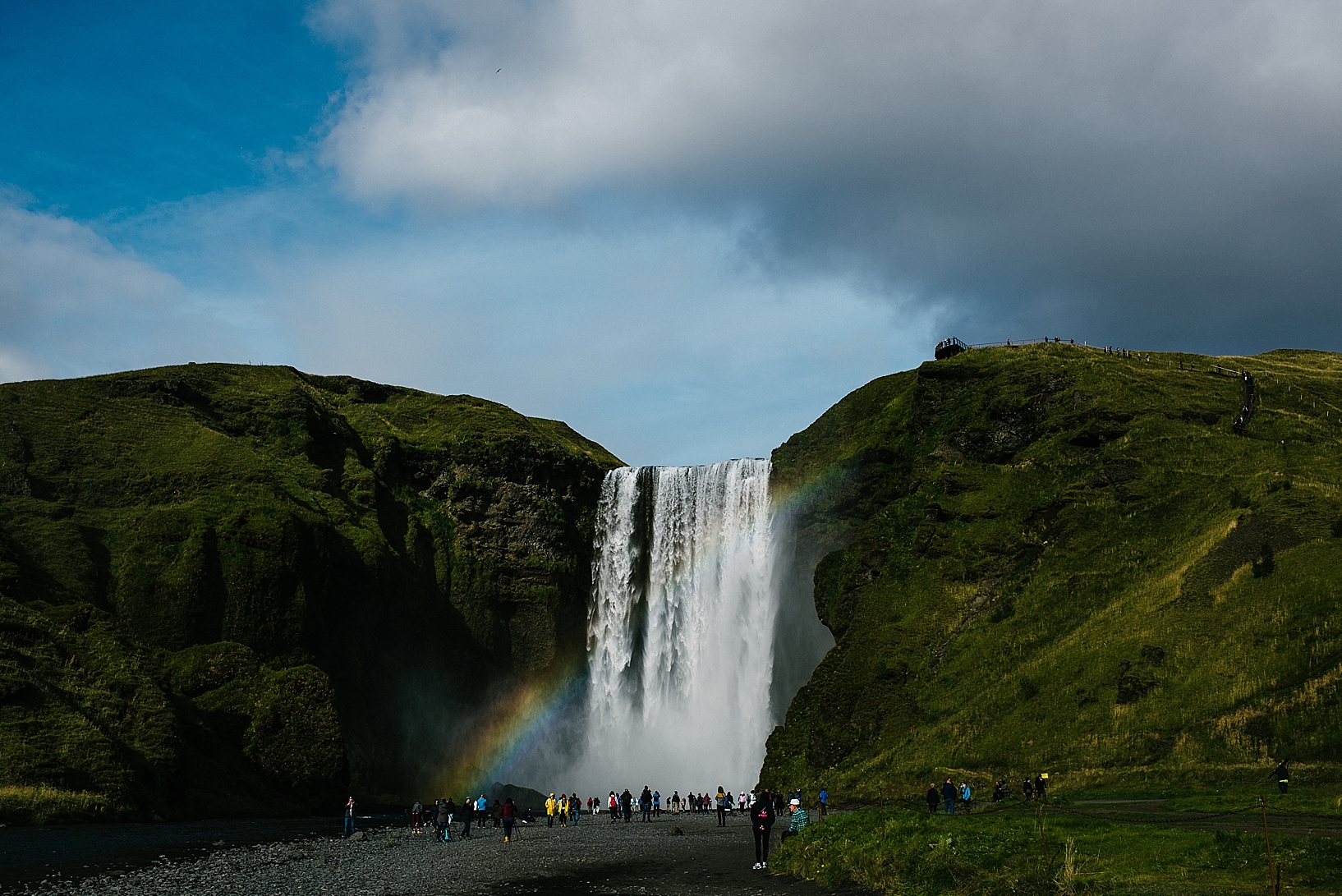 tourists standing in front of Skogafoss waterfall in Iceland