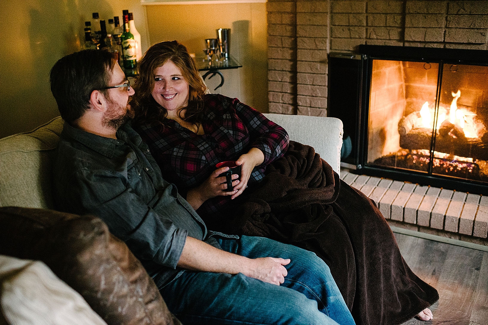 couple sitting on couch by fireplace
