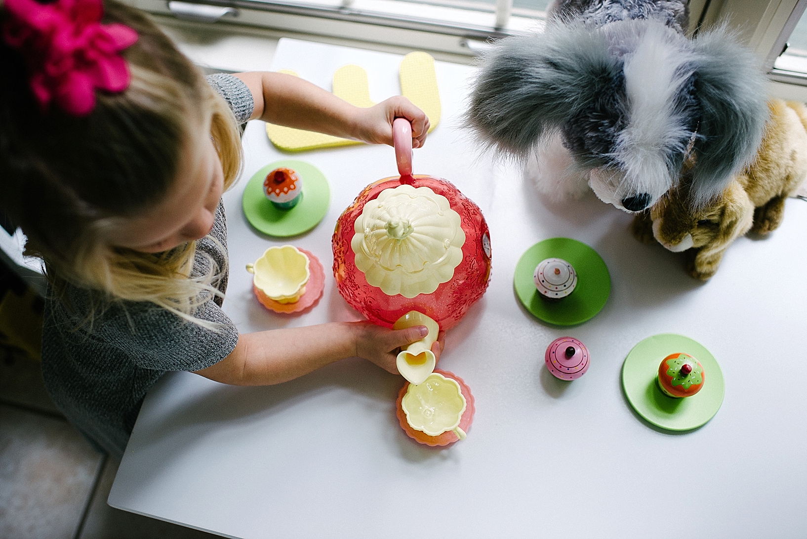 young blonde girl having tea party with stuffed animals